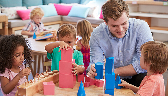 Junger Erzieher spielt mit Kinder im Kindergarten