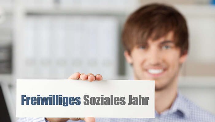 Junger Mann hält ein FSJ-Schild in der Hand